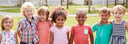 A diverse group of preschool-aged children posing together outside